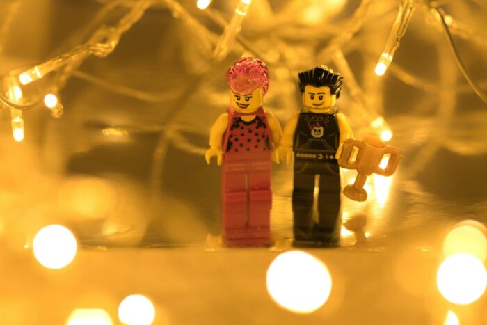 Lego figures holding a trophy stand in front of gold lighting